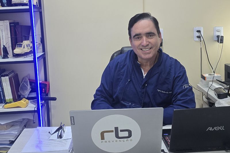 Dr. Rogério Boelter à mesa do consultório da RB Prevenção, com a estante de livros ao fundo