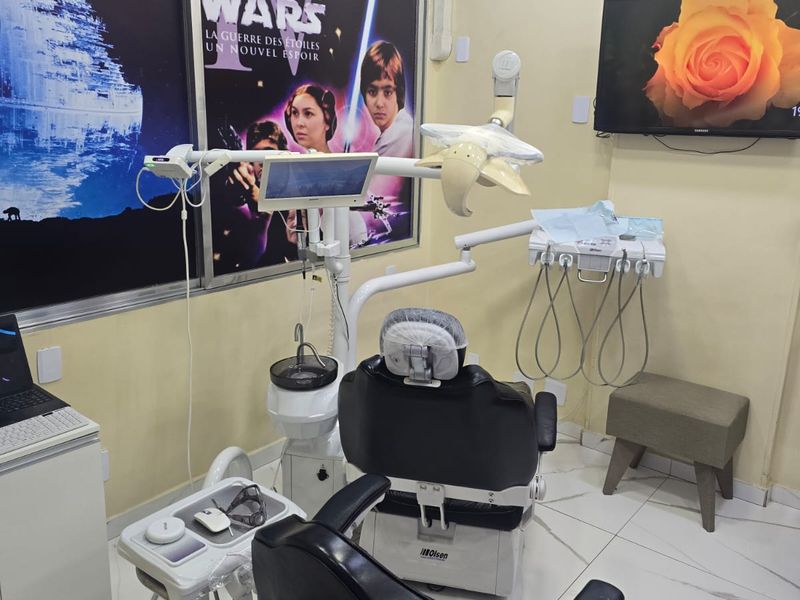 Sala de atendimento da RB Prevenção, em Madureira, com a cadeira odontológica e pôsteres na parede